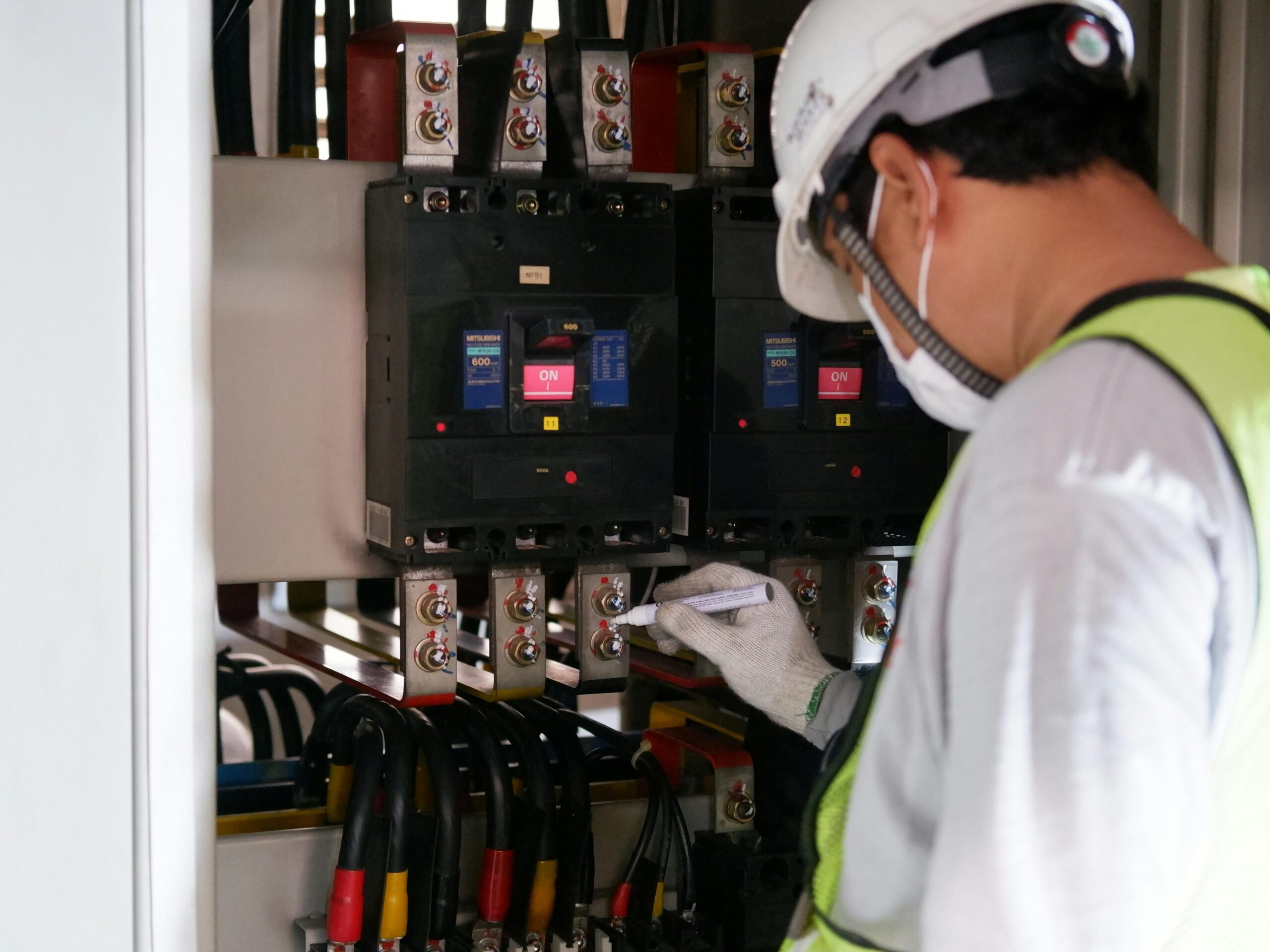 A man in a safety vest inspects electrical equipment, demonstrating maintenance practices for Sydney's electrical systems.